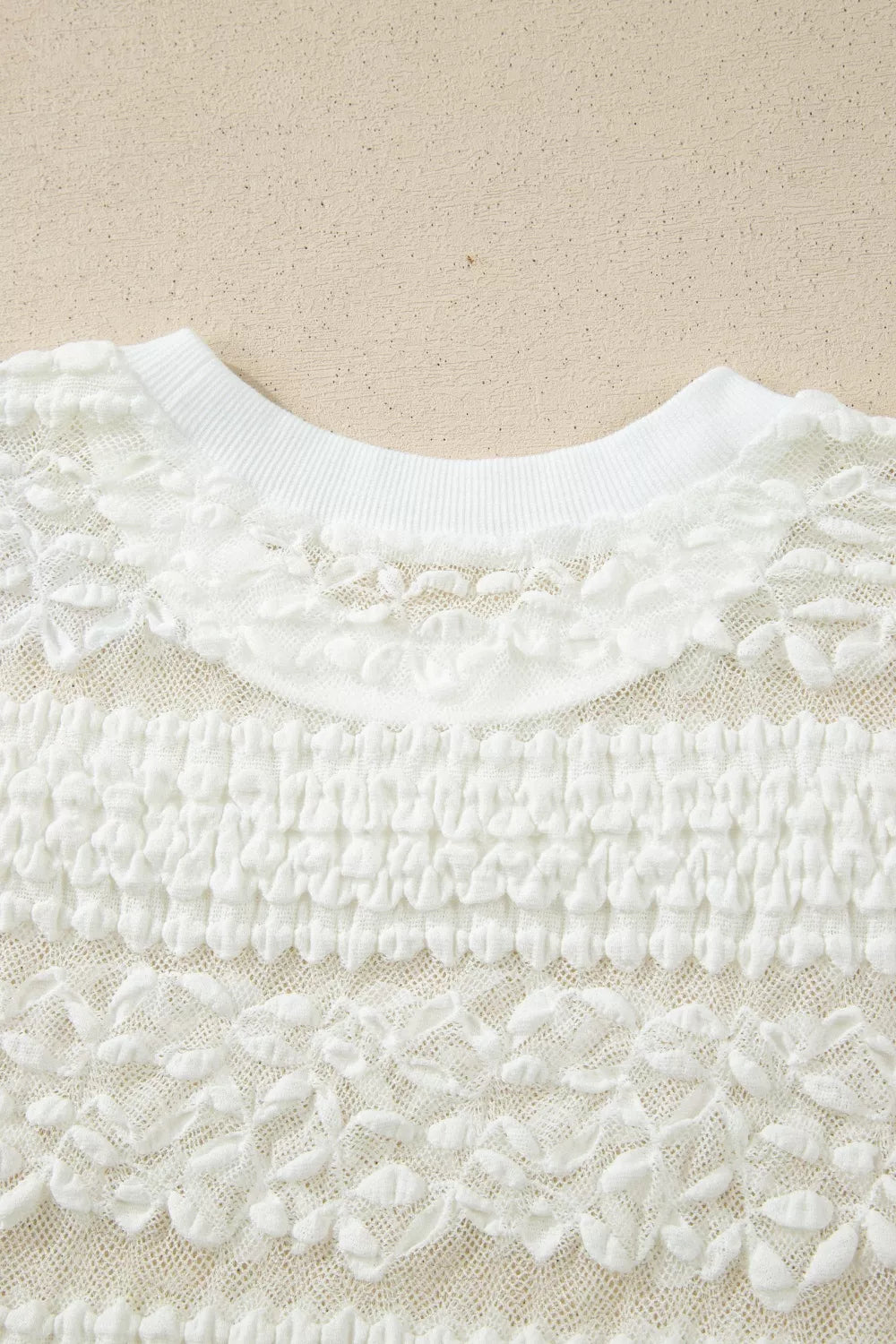 White sheer lace short sleeve tee with floral pattern, slightly stretchy fit, and delicate feminine texture styled with dark denim jeans.