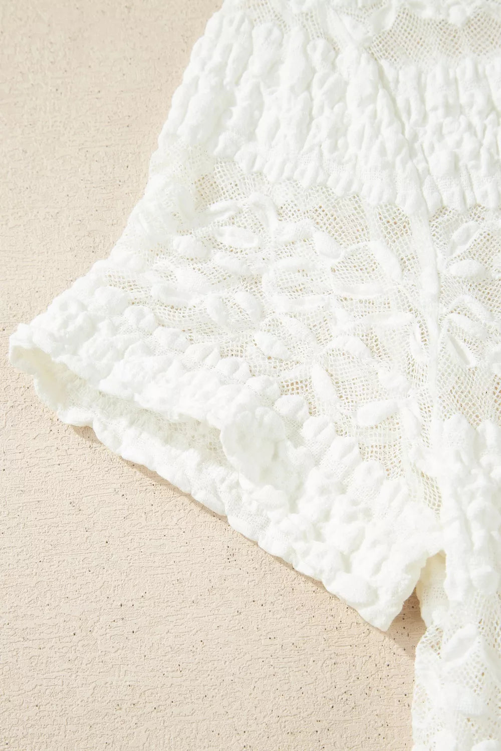 White sheer lace short sleeve tee with floral pattern, slightly stretchy fit, and delicate feminine texture styled with dark denim jeans.