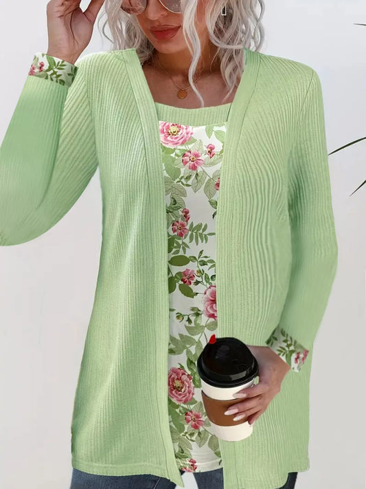 Woman wearing a faux two-piece top with a ribbed outer layer and floral underlayer at the neckline and sleeve cuffs.