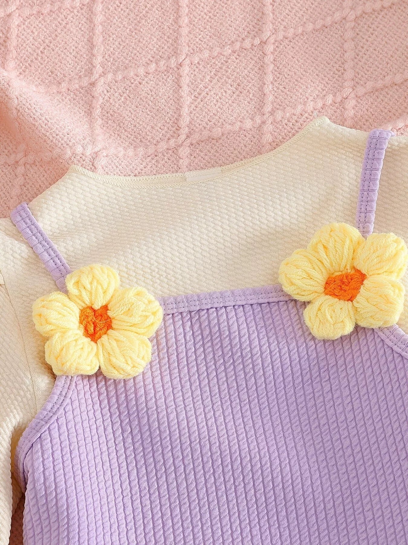 Children’s two-piece outfit with lavender ribbed pants, matching frill top, daisy appliqué details, and soft cotton-blend fabric.