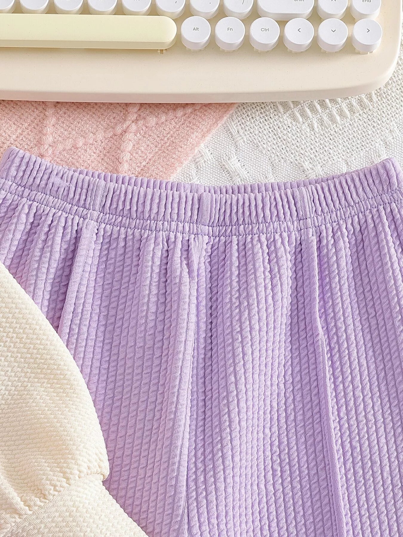 Children’s two-piece outfit with lavender ribbed pants, matching frill top, daisy appliqué details, and soft cotton-blend fabric.