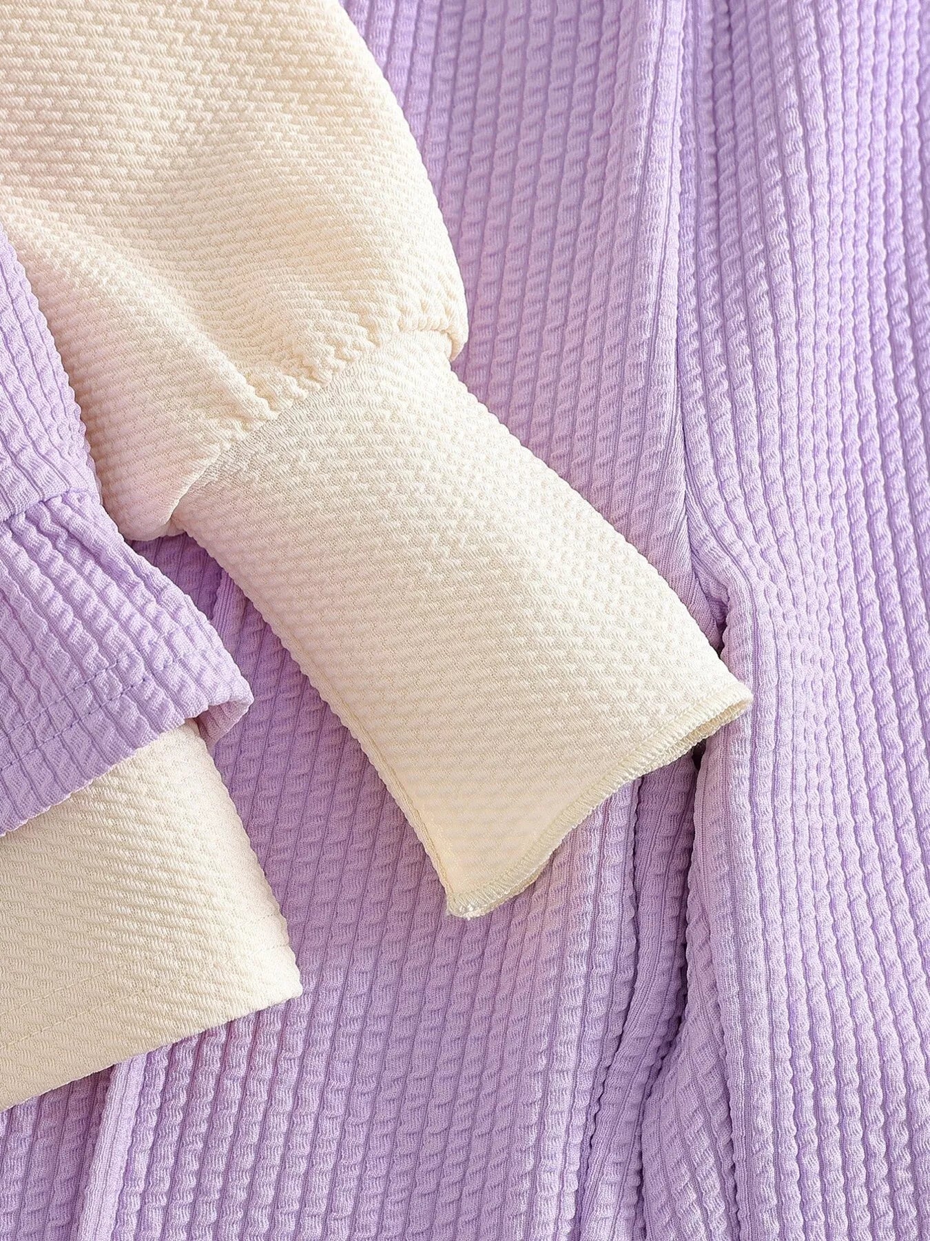 Children’s two-piece outfit with lavender ribbed pants, matching frill top, daisy appliqué details, and soft cotton-blend fabric.