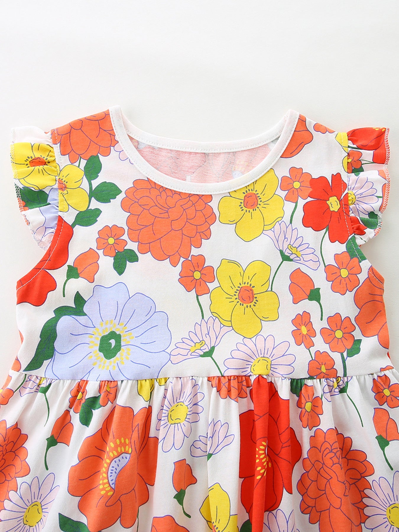 Girls cotton dress with colorful floral print, flutter sleeves, and a flowy skirt styled with white Mary Jane shoes.