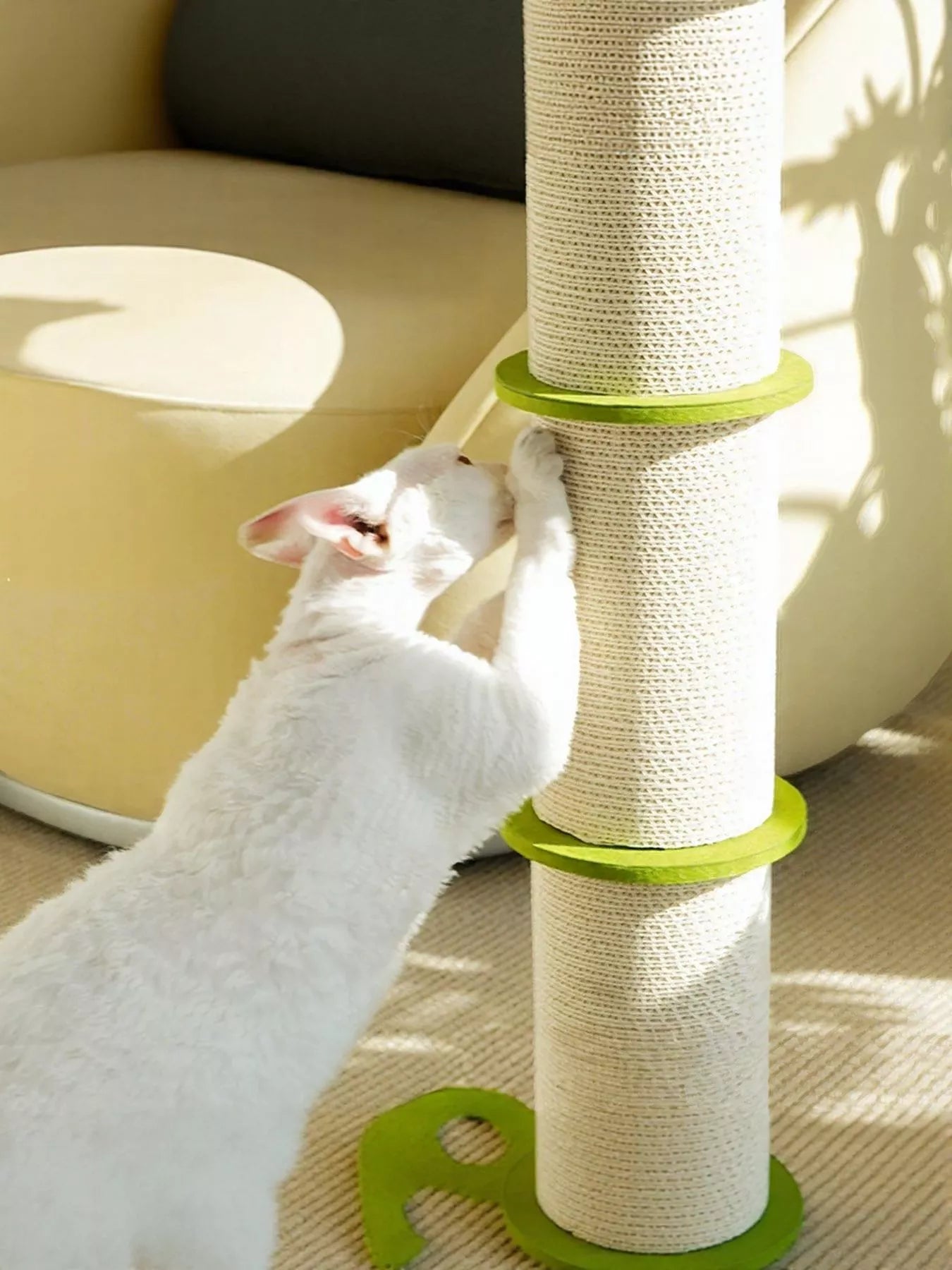 White cat stretching on modern green linen scratching tower with leaf accent