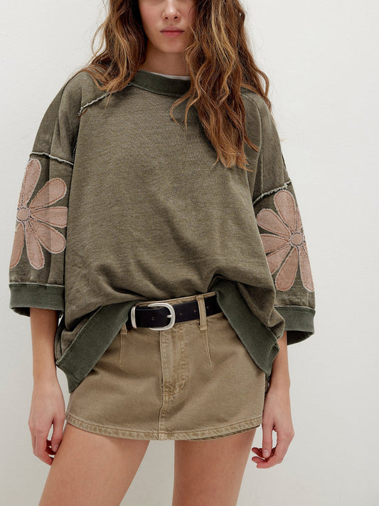 Relaxed pullover top with floral sleeve patch detail and exposed seams