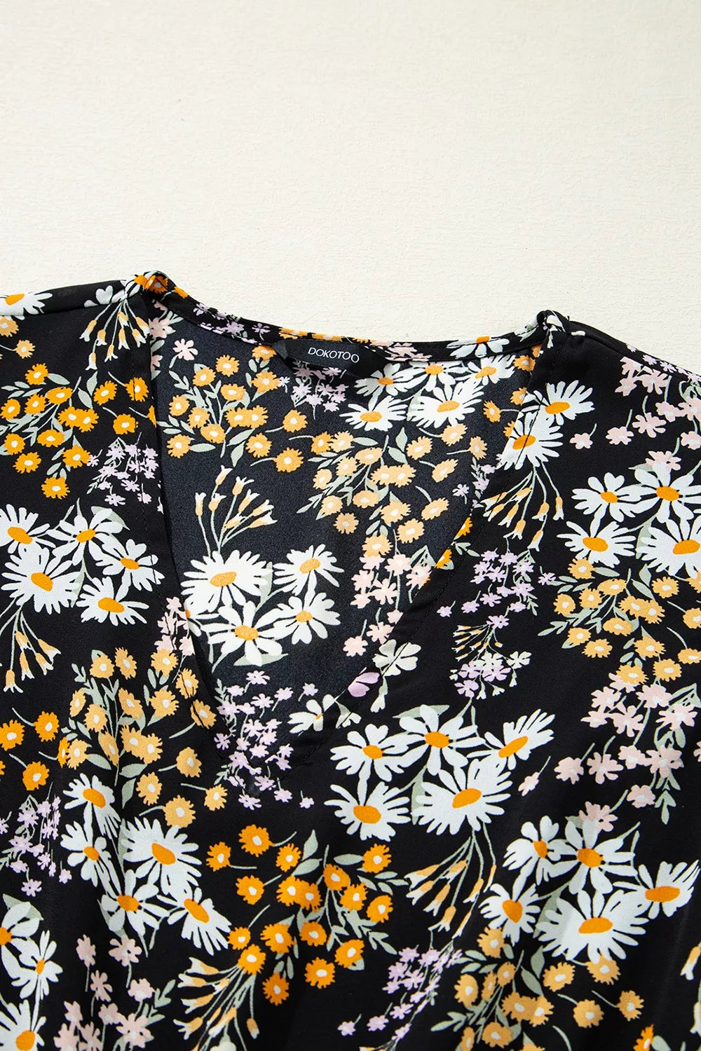 Black floral peplum blouse with smocked waist and short sleeves
