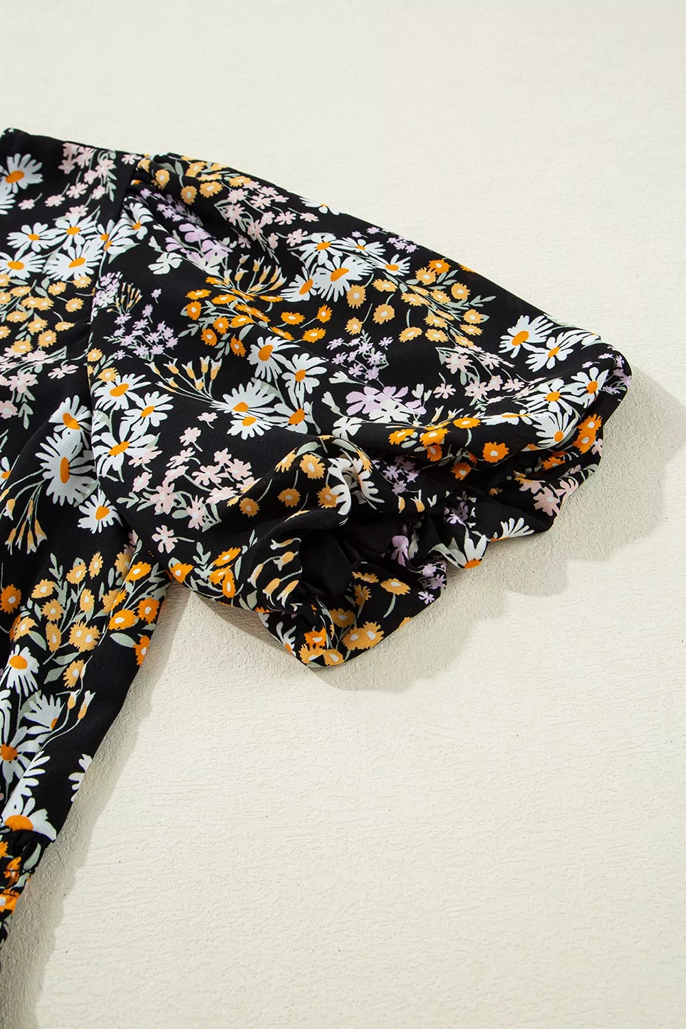 Black floral peplum blouse with smocked waist and short sleeves