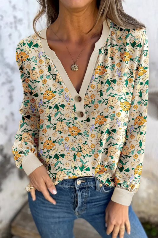 Cream floral long-sleeve blouse with a buttoned V-neckline and cuffed sleeves, paired with jeans.