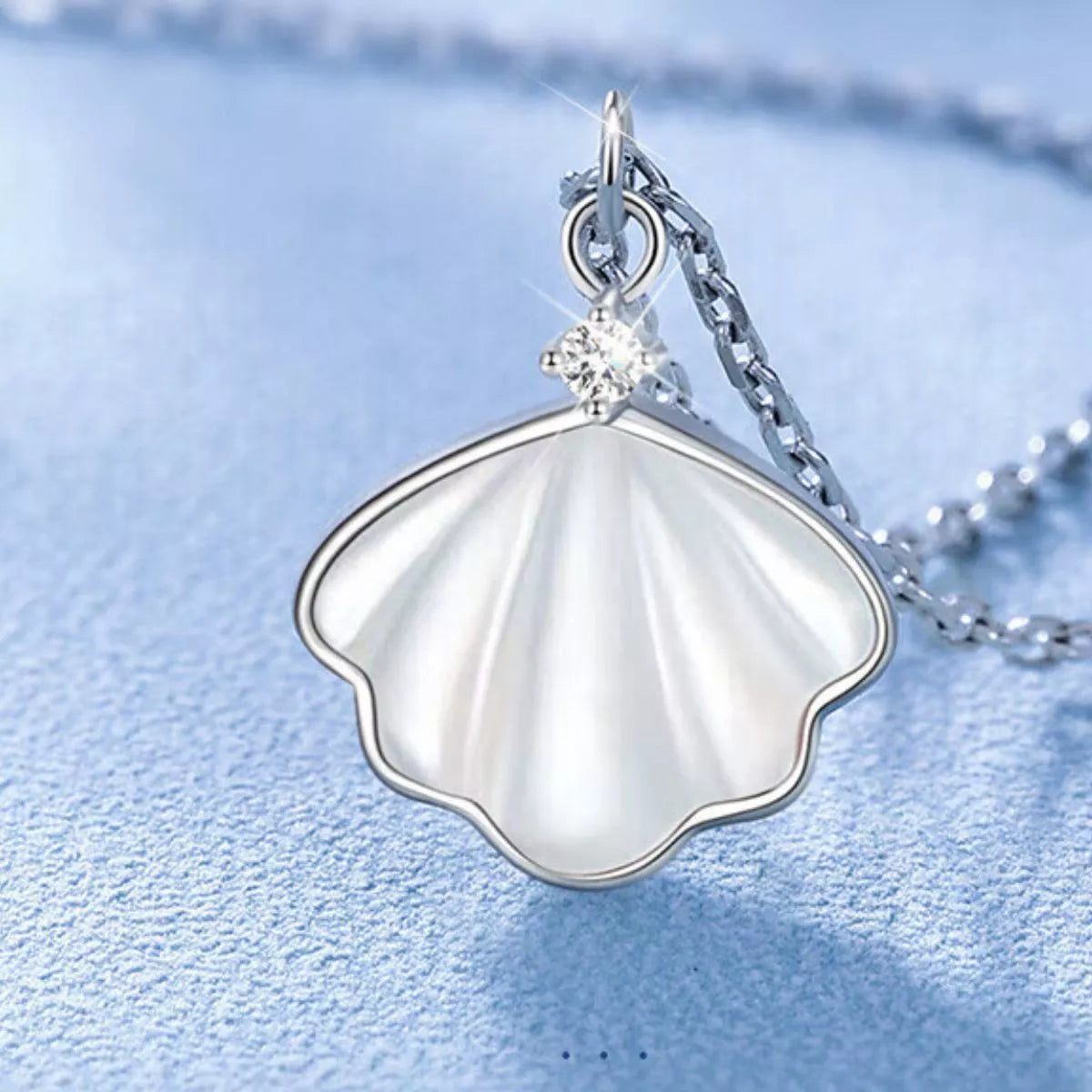 Sterling silver shell pendant necklace with zircon accent on a dainty chain, displayed in a matching navy jewelry box.