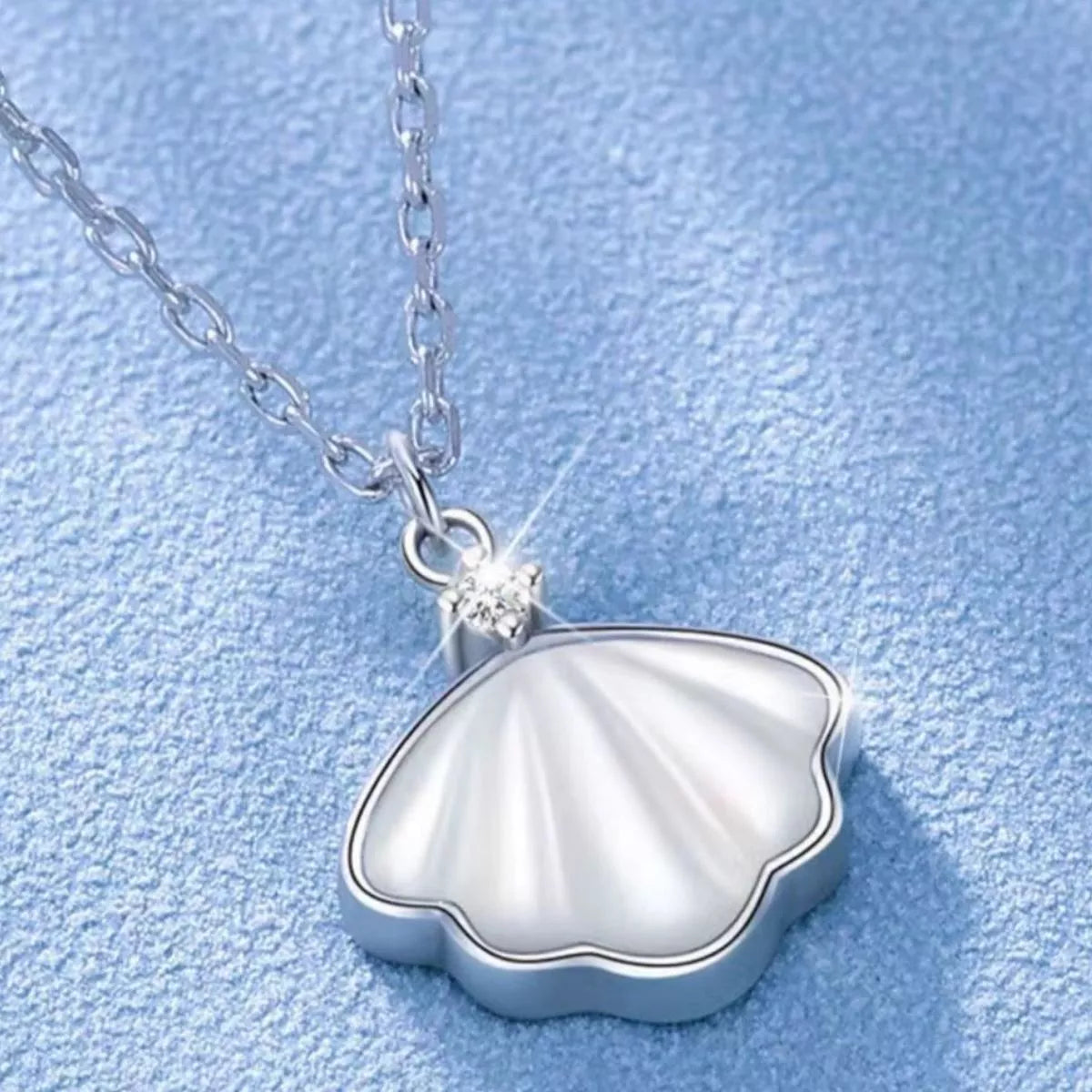 Sterling silver shell pendant necklace with zircon accent on a dainty chain, displayed in a matching navy jewelry box.