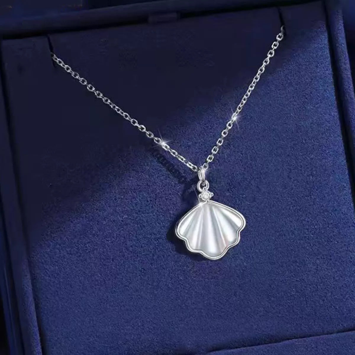 Sterling silver shell pendant necklace with zircon accent on a dainty chain, displayed in a matching navy jewelry box.