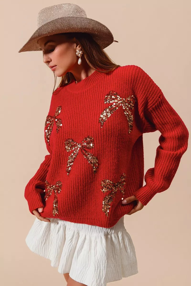Woman wearing a red ribbed sweater with gold sequin bow designs — festive holiday sweater from A Whimsical Affair.