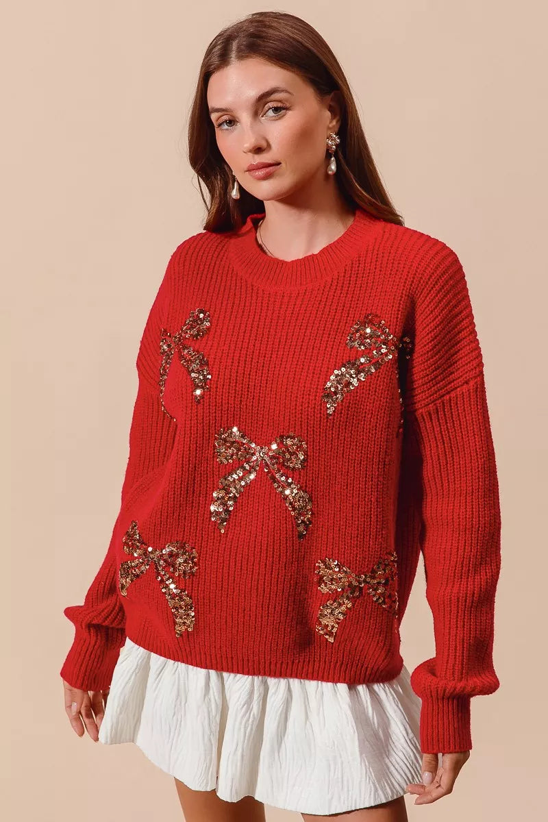 Woman wearing a red ribbed sweater with gold sequin bow designs — festive holiday sweater from A Whimsical Affair.