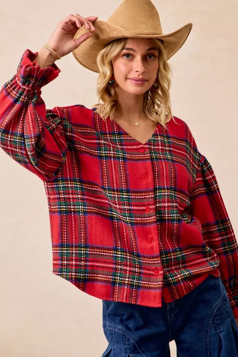 Woman wearing a festive red plaid button-front flounce-sleeve jacket with a v-neckline, styled for the holiday season.