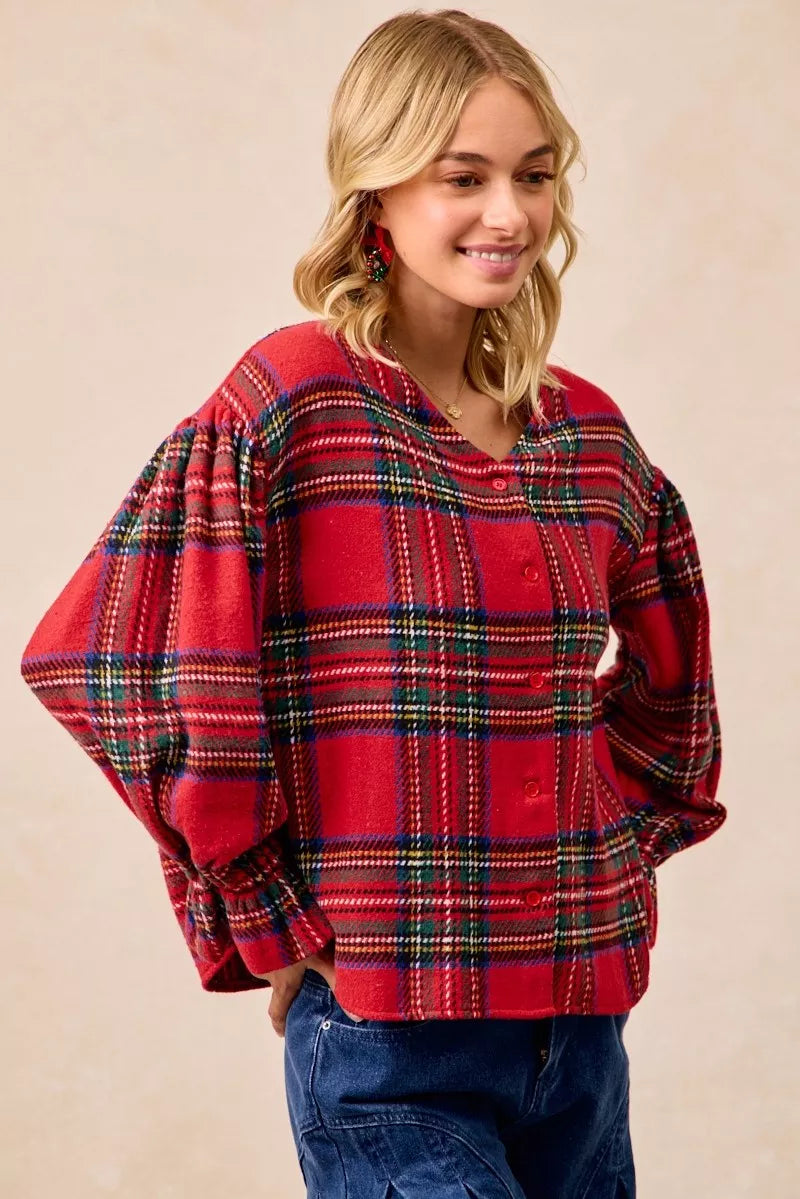Woman wearing a festive red plaid button-front flounce-sleeve jacket with a v-neckline, styled for the holiday season.
