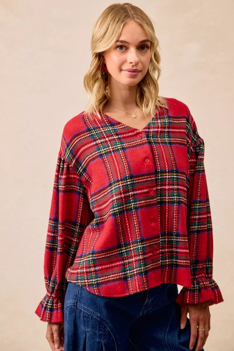 Woman wearing a festive red plaid button-front flounce-sleeve jacket with a v-neckline, styled for the holiday season.