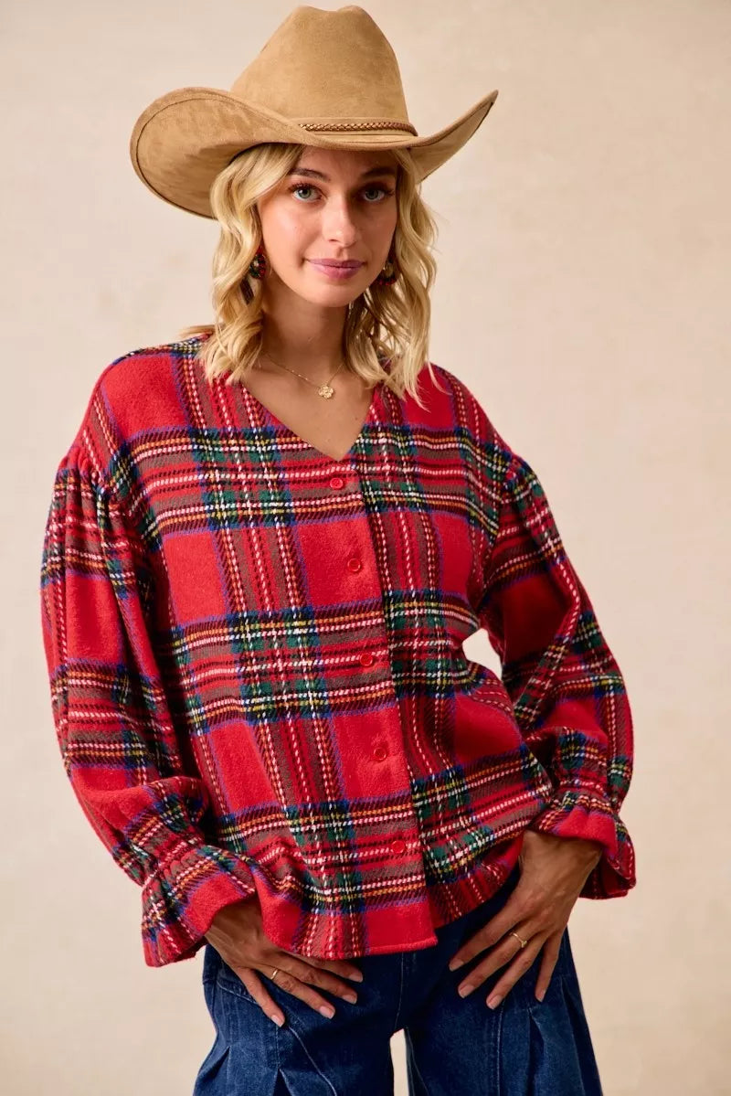 Woman wearing a festive red plaid button-front flounce-sleeve jacket with a v-neckline, styled for the holiday season.