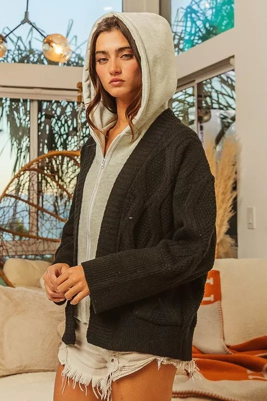 Woman wearing a black and gray knit hoodie sweater jacket indoors with casual outfit