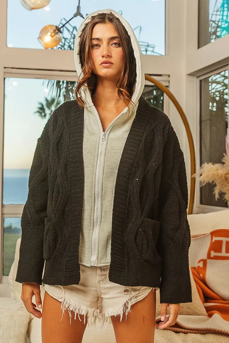 Woman wearing a black and gray knit hoodie sweater jacket indoors with casual outfit