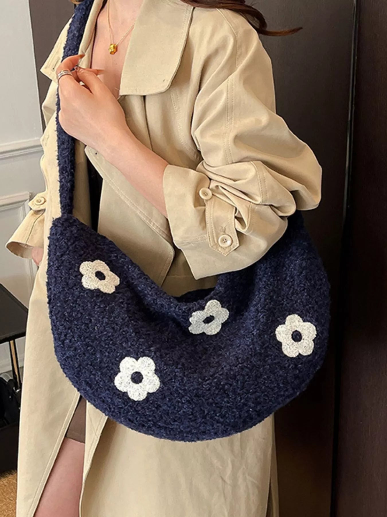 Navy plush shoulder bag with white flower appliqués and curved silhouette