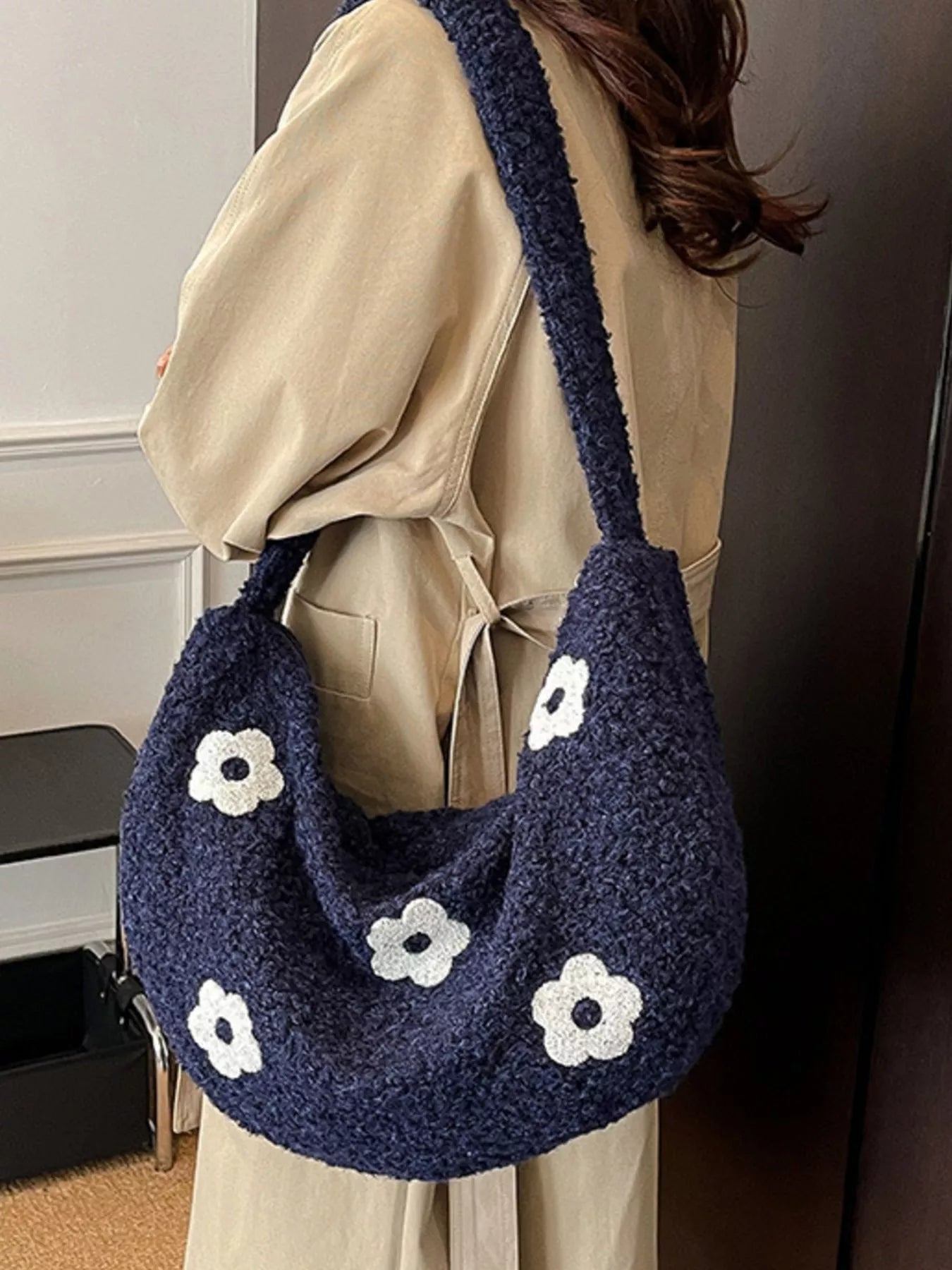 Navy plush shoulder bag with white flower appliqués and curved silhouette