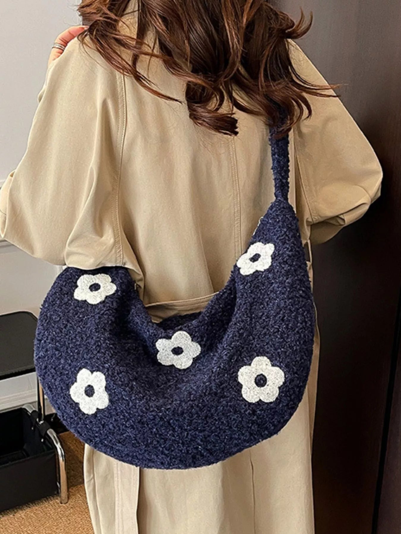 Navy plush shoulder bag with white flower appliqués and curved silhouette
