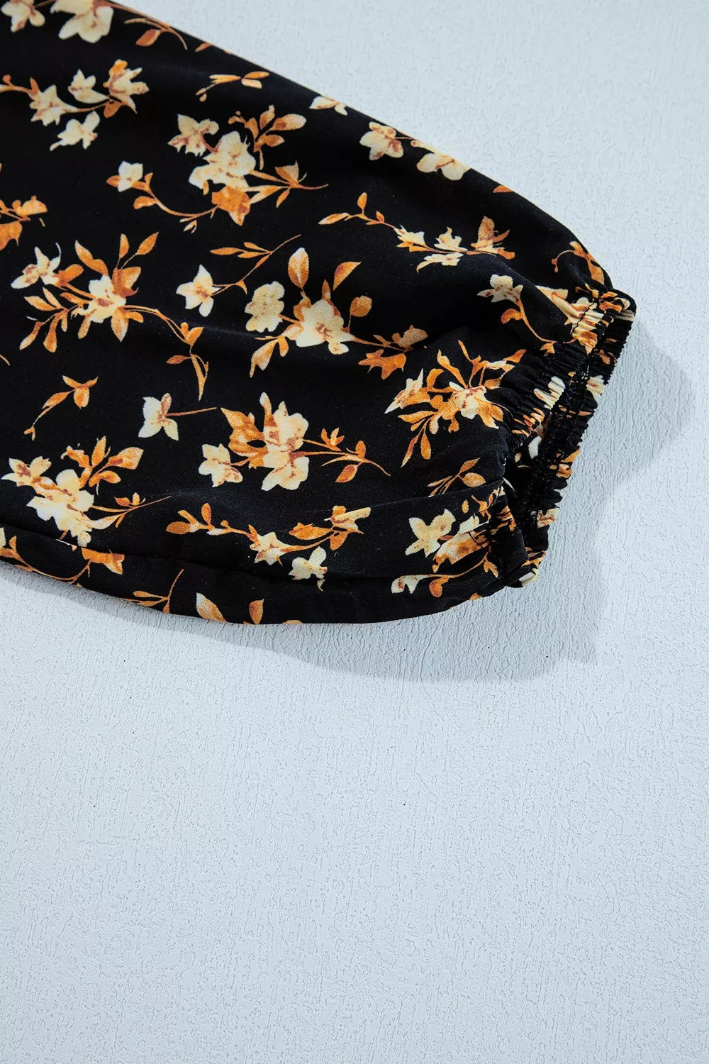 Black floral smocked long sleeve blouse with peplum hem