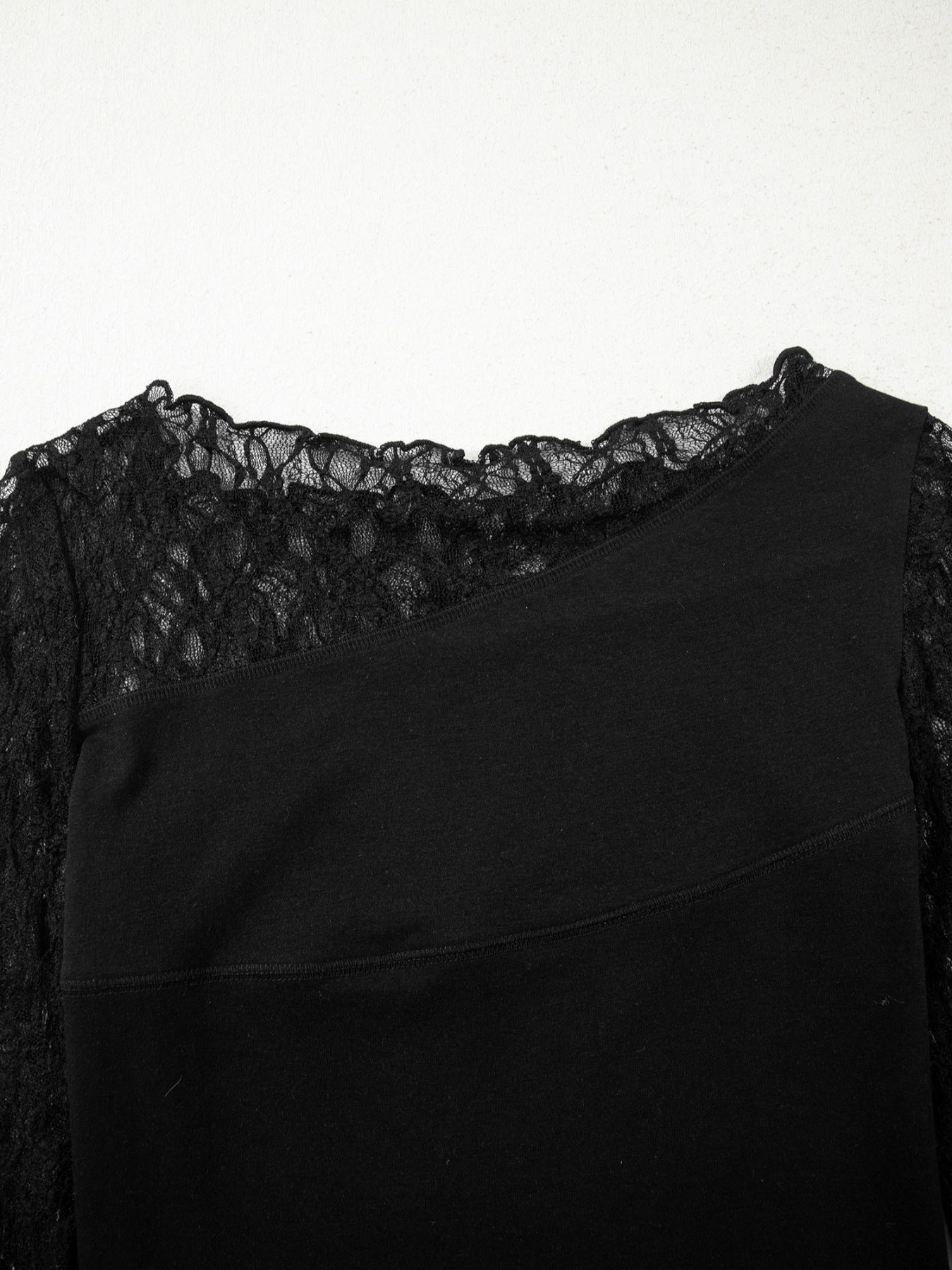 Woman wearing a black long sleeve top with sheer floral lace sleeves and trim