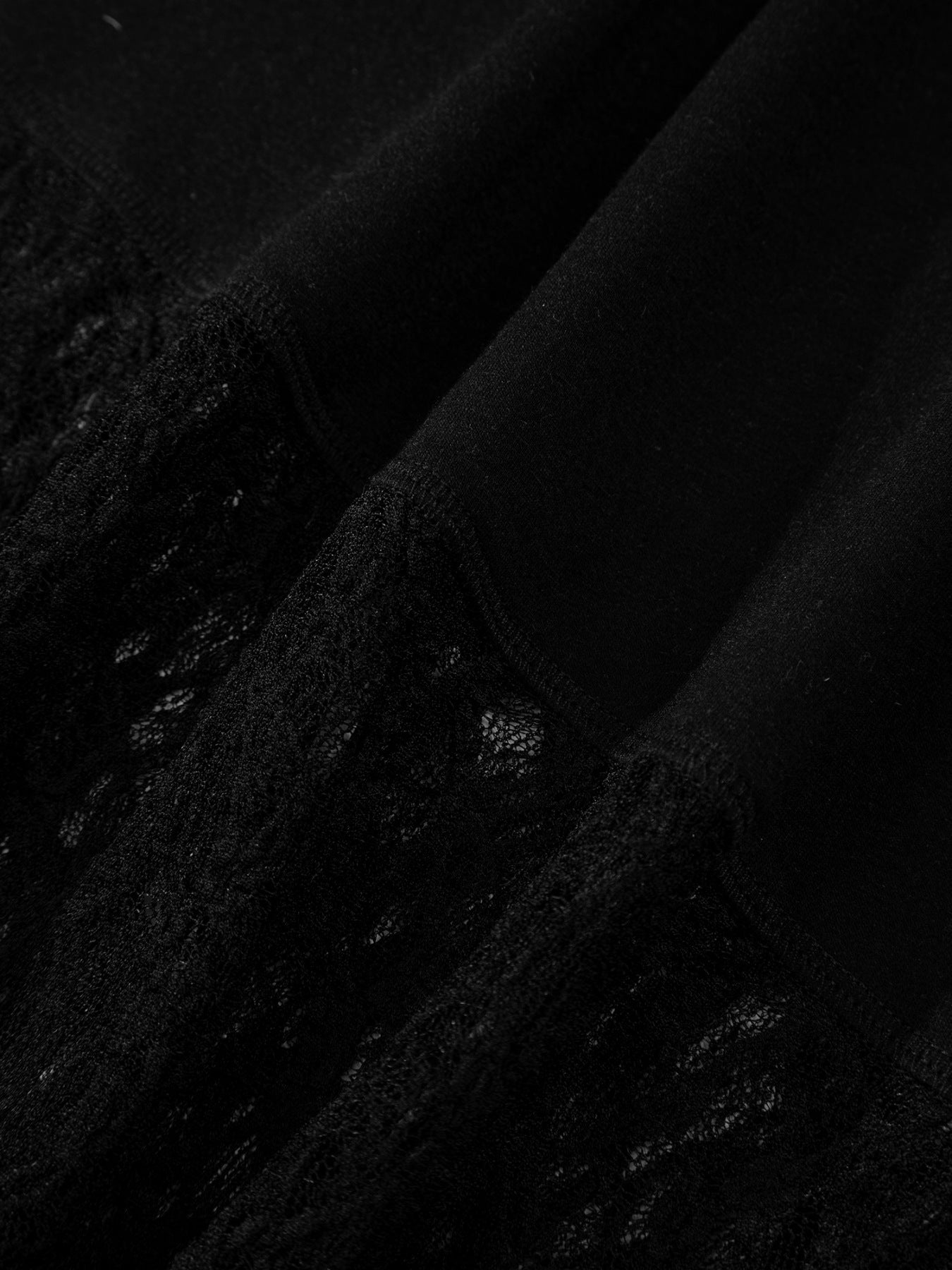 Woman wearing a black long sleeve top with sheer floral lace sleeves and trim
