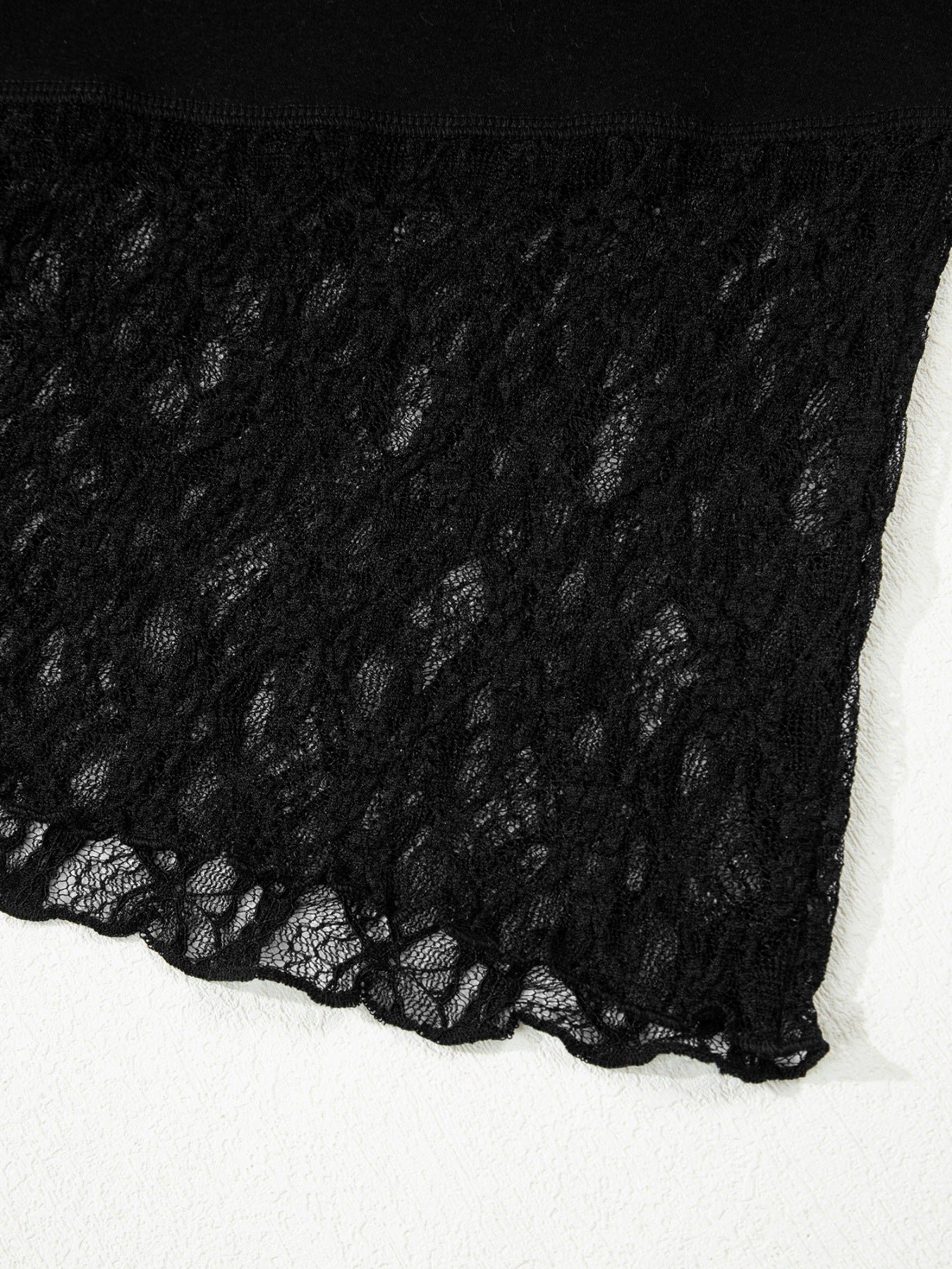 Woman wearing a black long sleeve top with sheer floral lace sleeves and trim