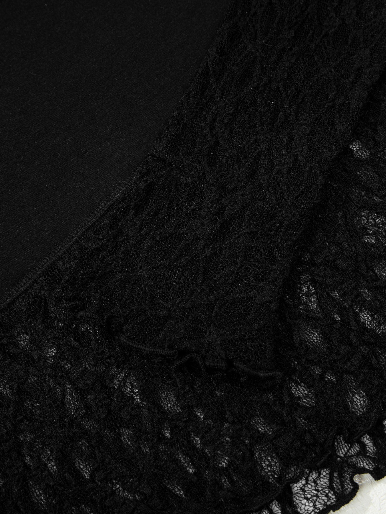 Woman wearing a black long sleeve top with sheer floral lace sleeves and trim