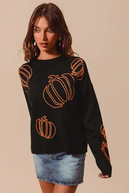 Woman wearing a black knit sweater with orange pumpkin outlines, styled with denim skirt — cozy Halloween pullover from A Whimsical Affair.