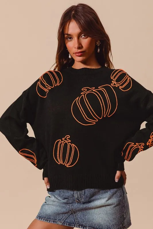 Woman wearing a black knit sweater with orange pumpkin outlines, styled with denim skirt — cozy Halloween pullover from A Whimsical Affair.