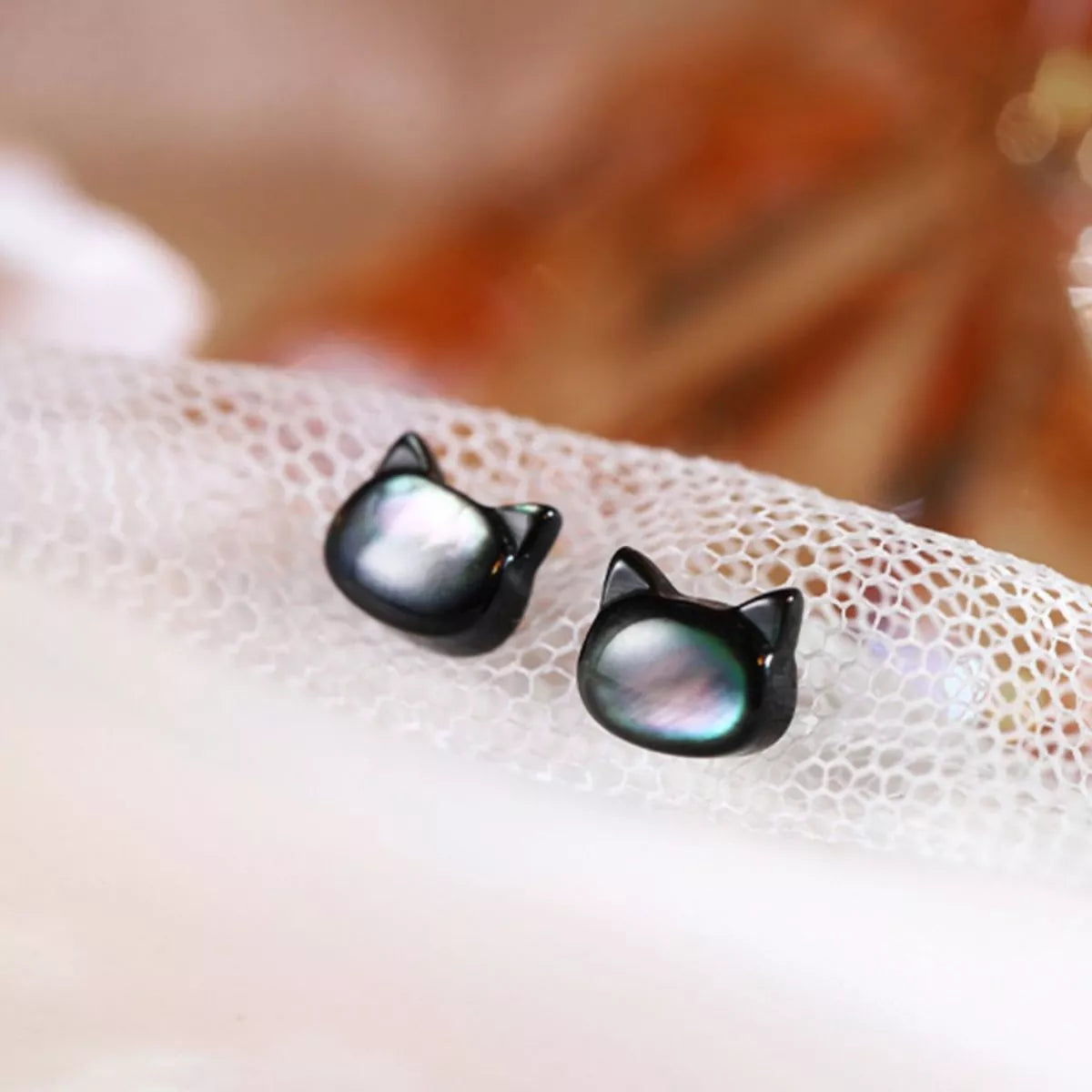 Black cat-shaped sterling silver stud earrings with iridescent shell inlay on soft white background