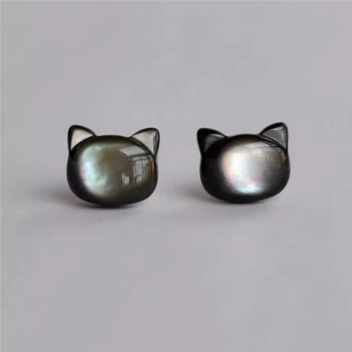 Black cat-shaped sterling silver stud earrings with iridescent shell inlay on soft white background