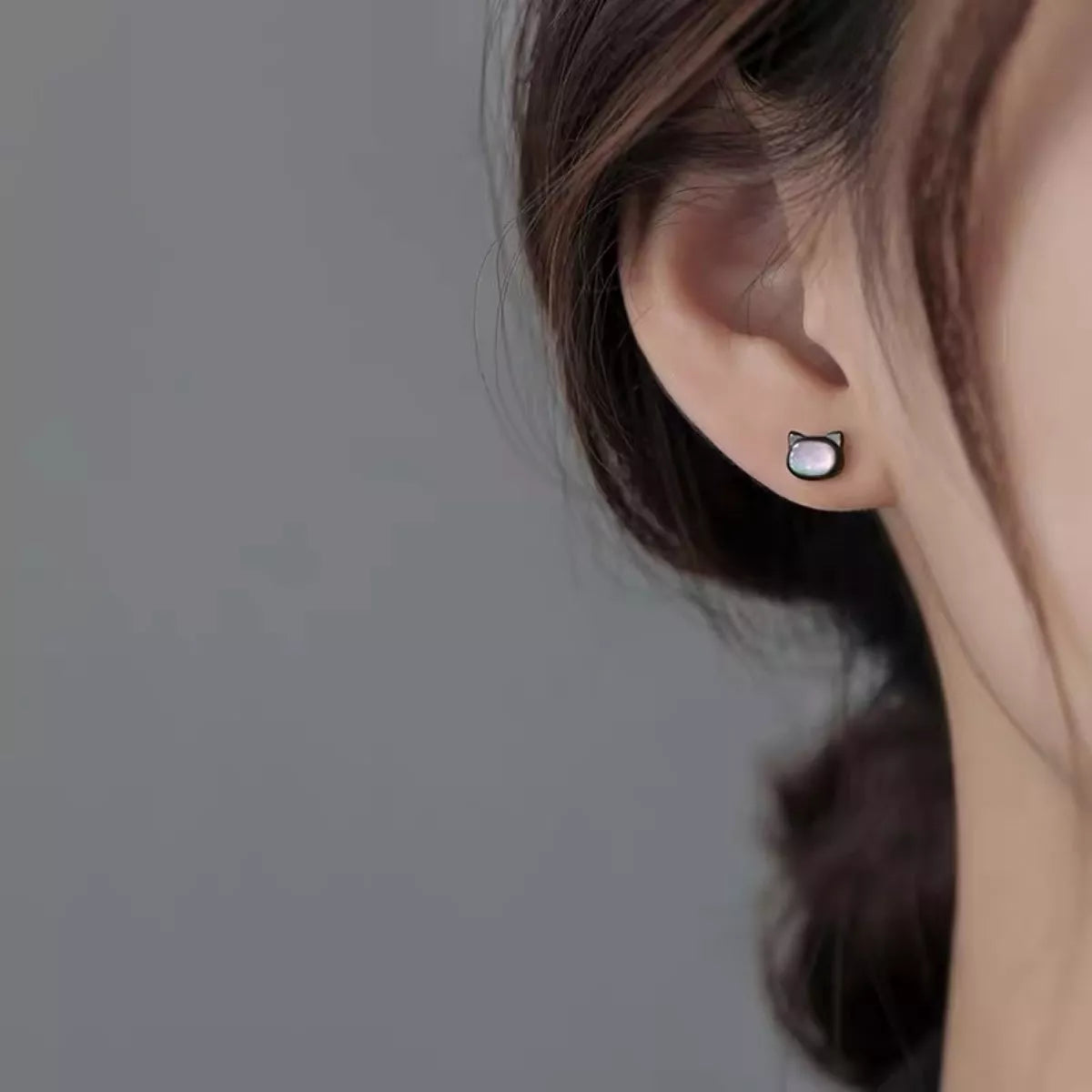 Black cat-shaped sterling silver stud earrings with iridescent shell inlay on soft white background