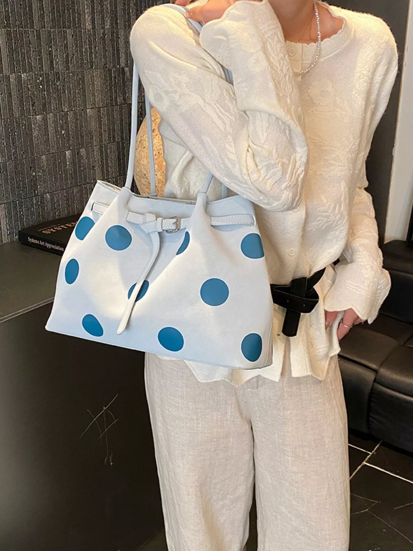 Medium white slouch shoulder bag with bold blue polka dots, PU leather material, adjustable strap detail, and relaxed everyday styling.