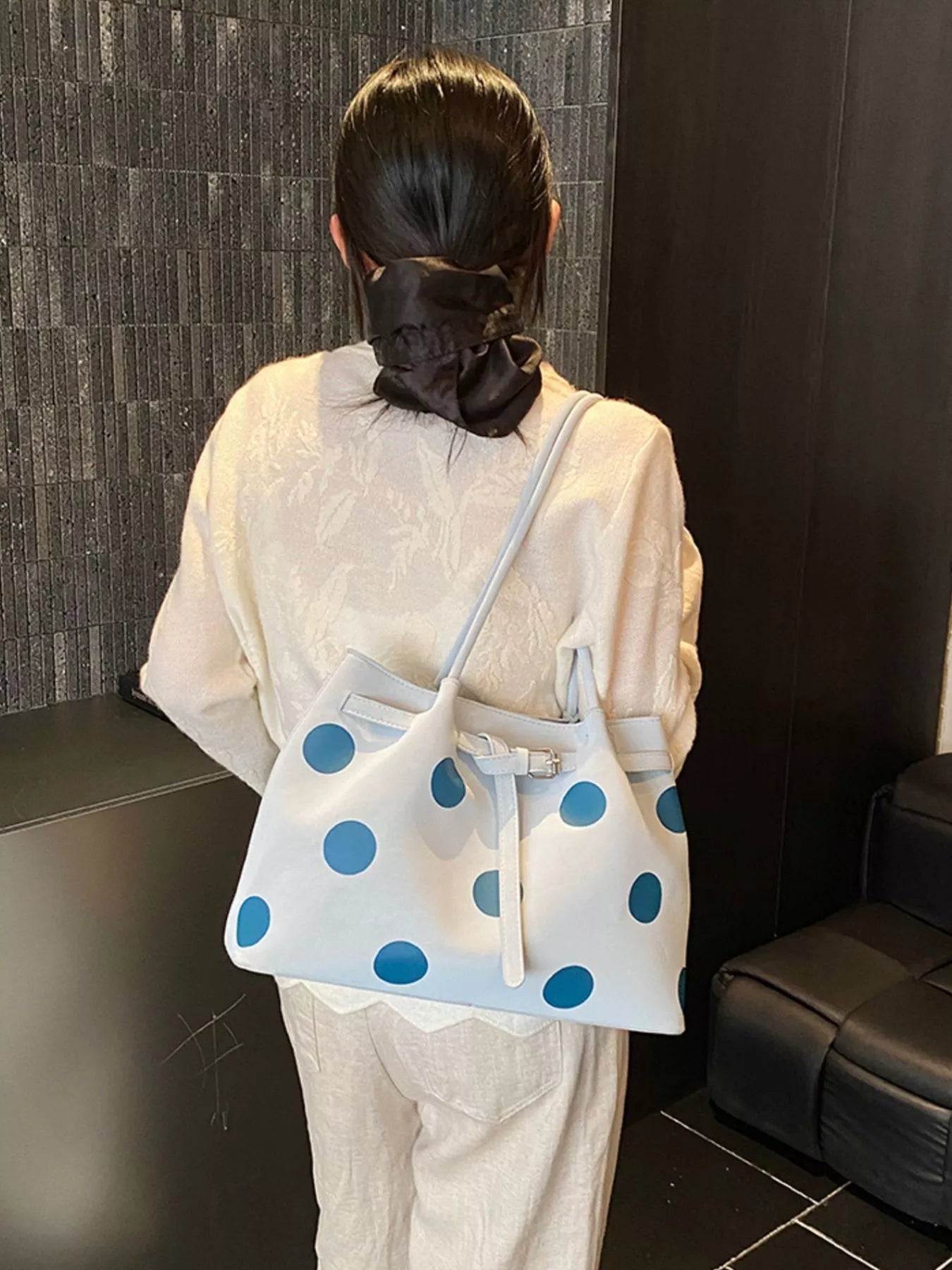 Medium white slouch shoulder bag with bold blue polka dots, PU leather material, adjustable strap detail, and relaxed everyday styling.