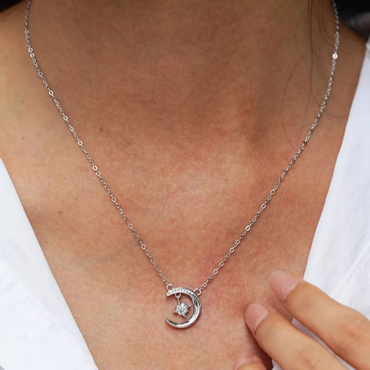 Sterling silver crescent moon necklace with a sparkling moissanite star pendant on a delicate silver chain.