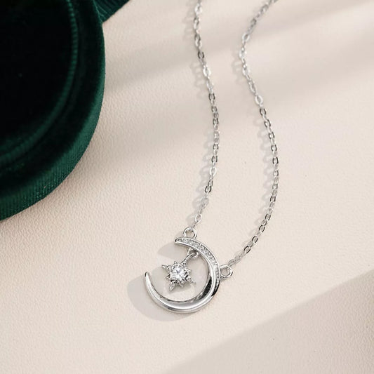 Sterling silver crescent moon necklace with a sparkling moissanite star pendant on a delicate silver chain.