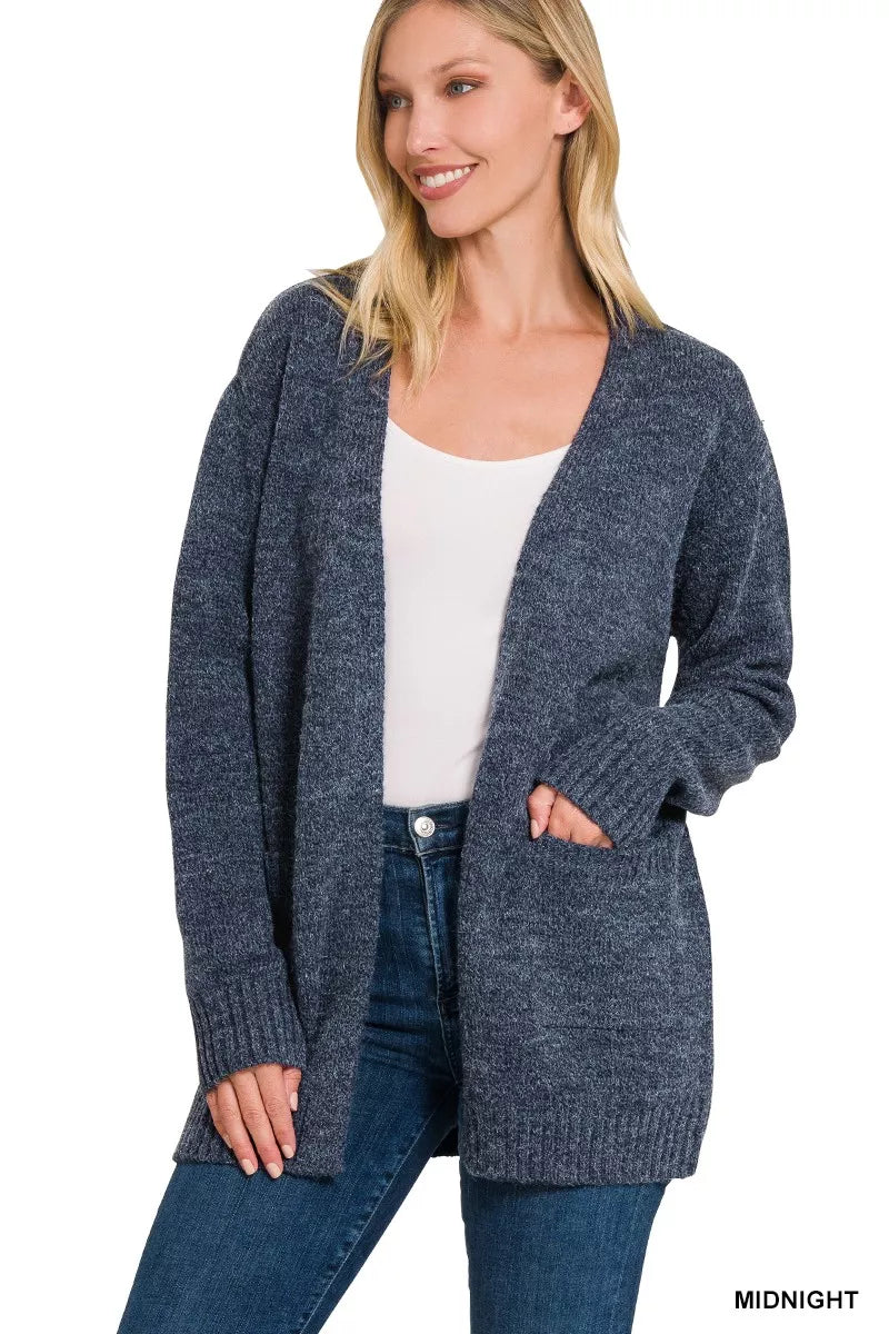 Open-front knit cardigan with front pockets, ribbed trim, long sleeves, and a relaxed slightly stretchy fit styled with jeans.