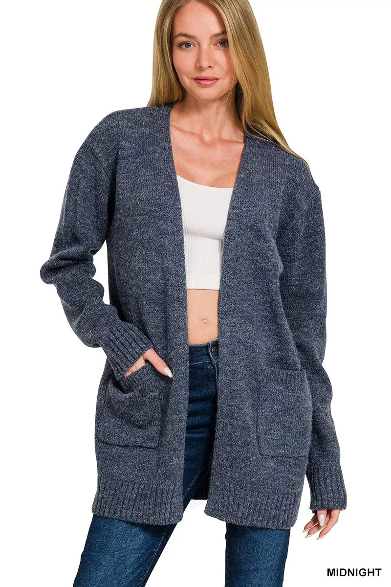 Open-front knit cardigan with front pockets, ribbed trim, long sleeves, and a relaxed slightly stretchy fit styled with jeans.