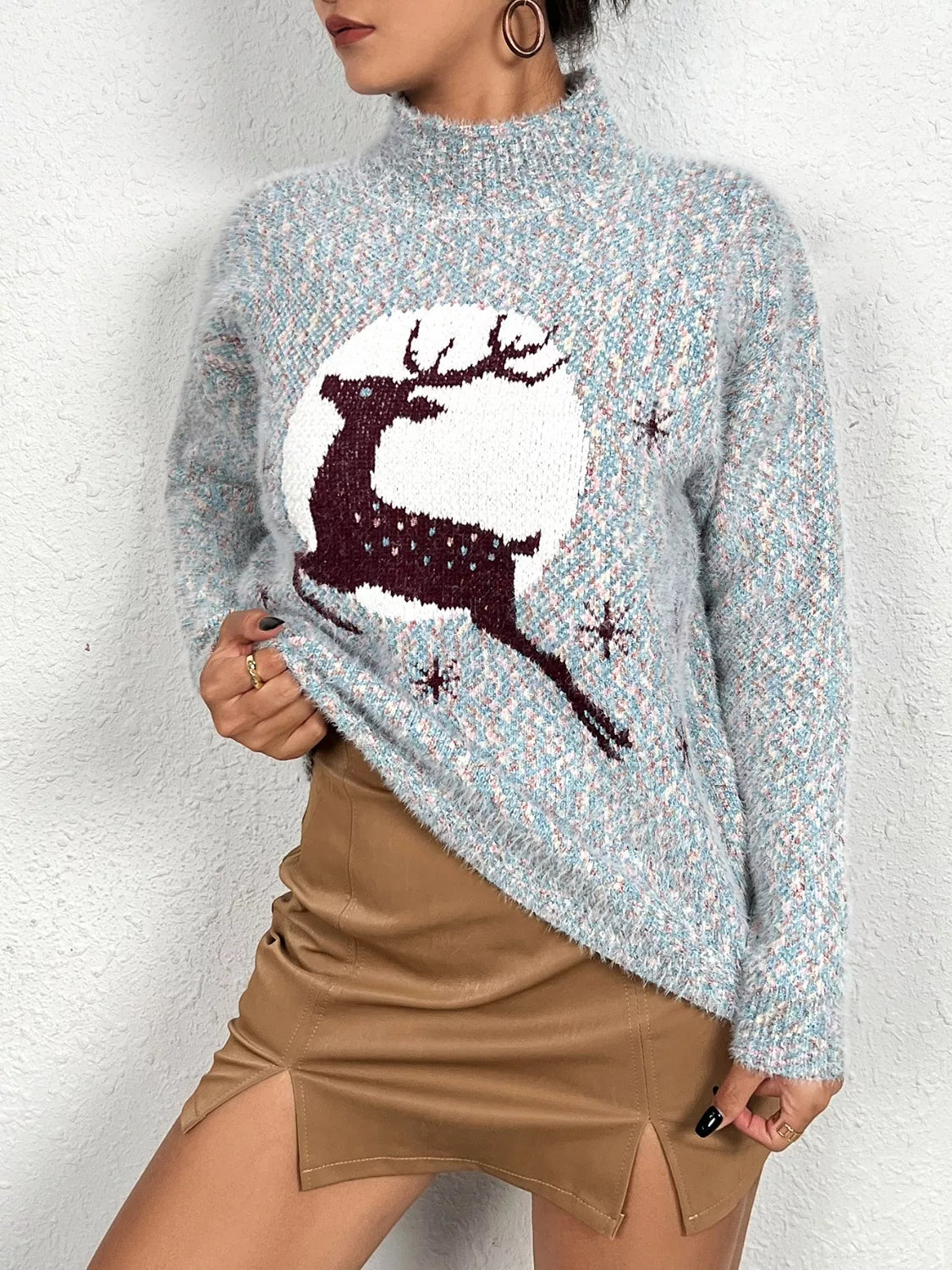 Soft knit sweater featuring a reindeer silhouette against a full moon design, styled with a tan mini skirt.