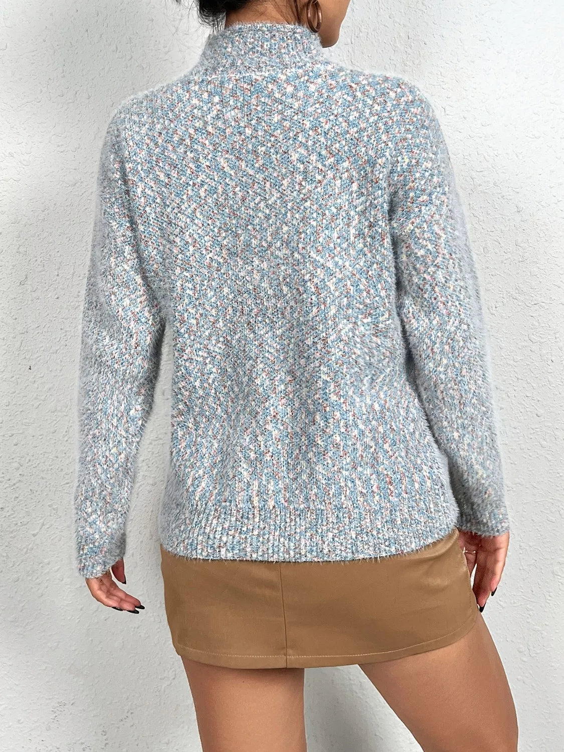 Soft knit sweater featuring a reindeer silhouette against a full moon design, styled with a tan mini skirt.