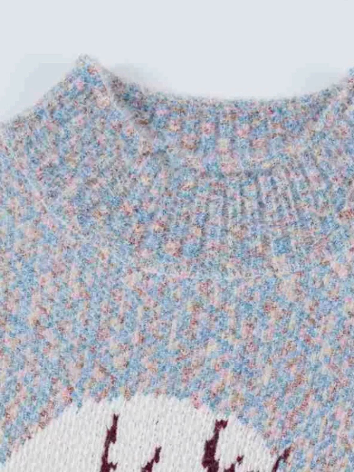 Soft knit sweater featuring a reindeer silhouette against a full moon design, styled with a tan mini skirt.