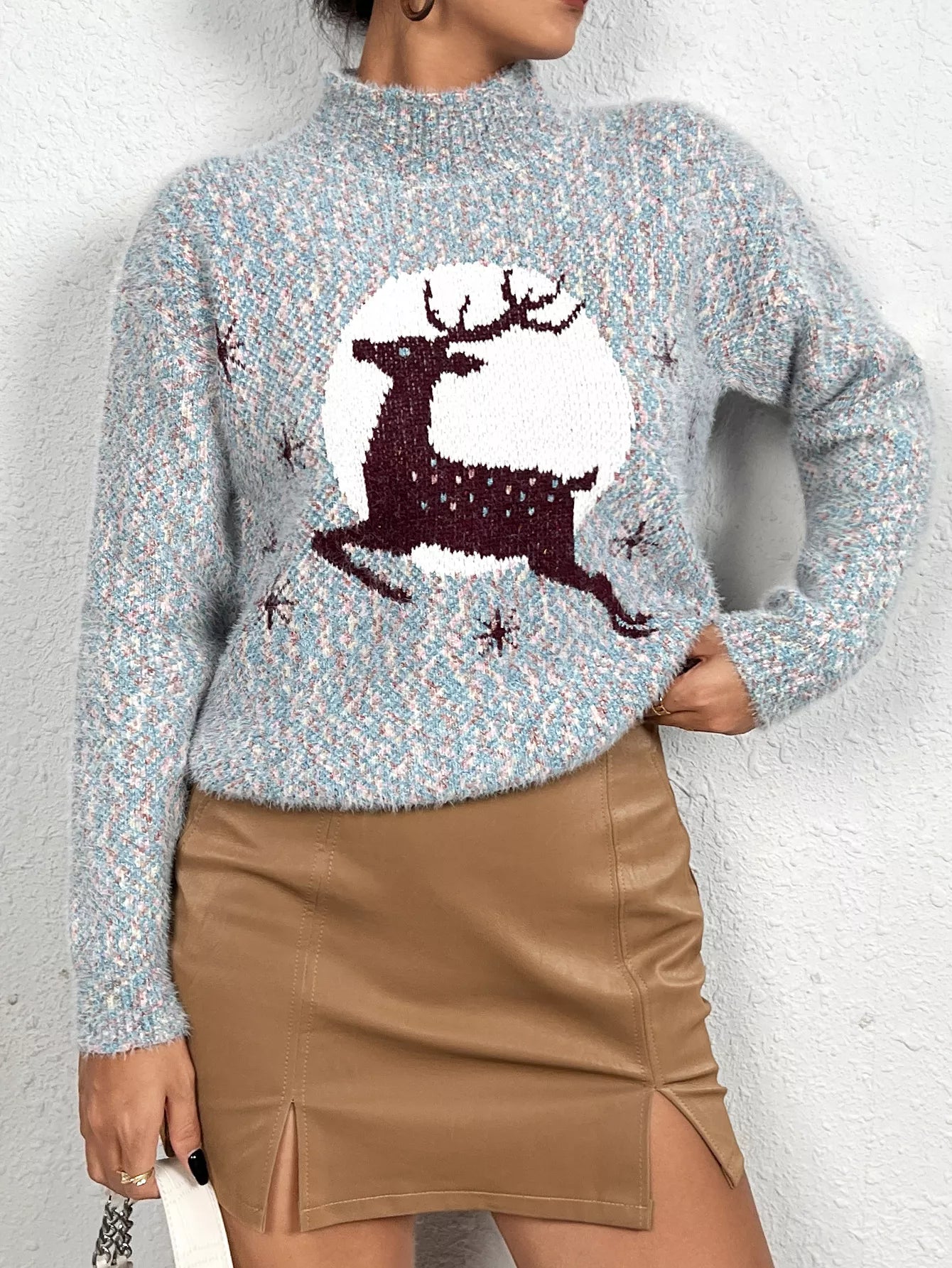 Soft knit sweater featuring a reindeer silhouette against a full moon design, styled with a tan mini skirt.