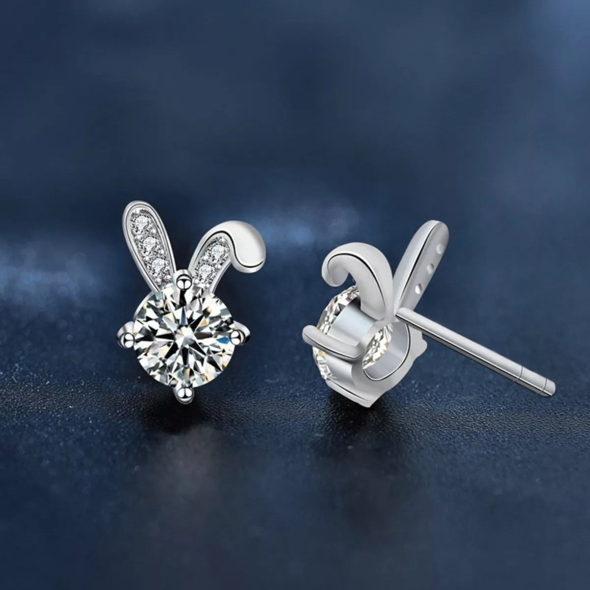 Platinum plated sterling silver bunny stud earrings featuring sparkling moissanite stones on a dark background