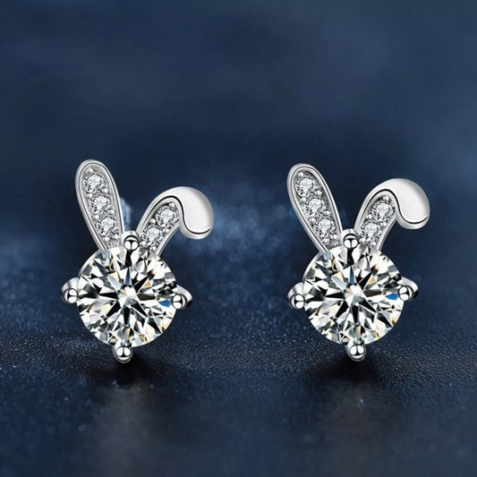 Platinum plated sterling silver bunny stud earrings featuring sparkling moissanite stones on a dark background