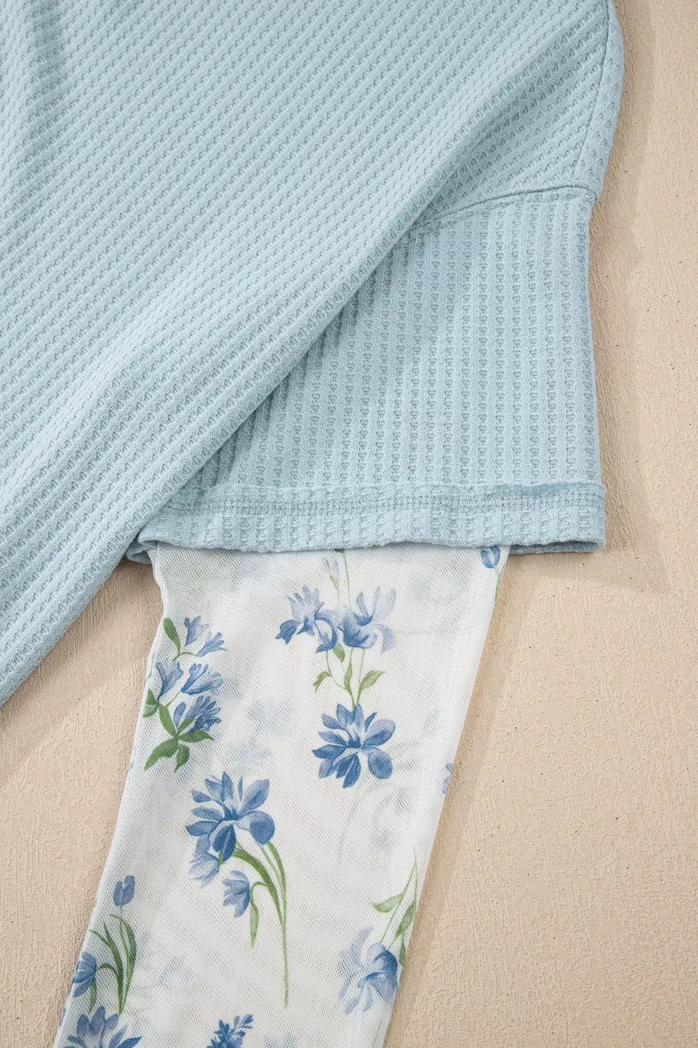 soft blue waffle-knit top with floral mesh layered sleeves and relaxed feminine silhouette