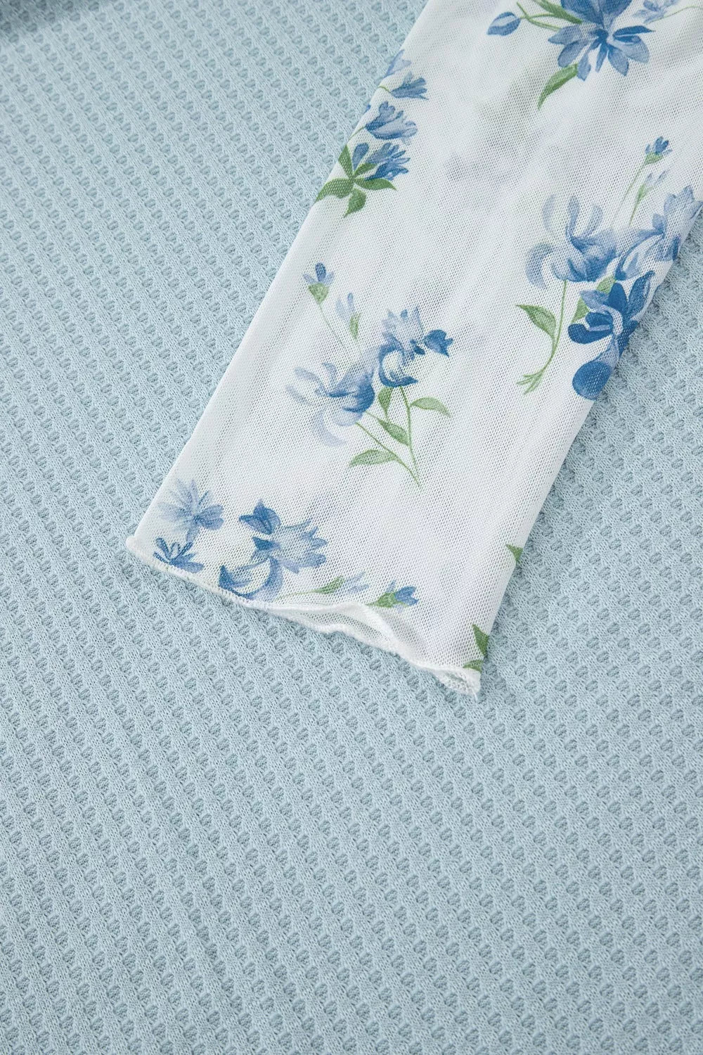 soft blue waffle-knit top with floral mesh layered sleeves and relaxed feminine silhouette
